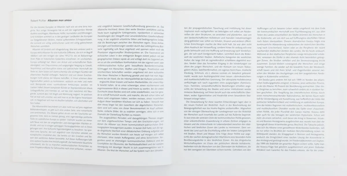 Open book with dense German text across two pages, lying flat on a white surface.