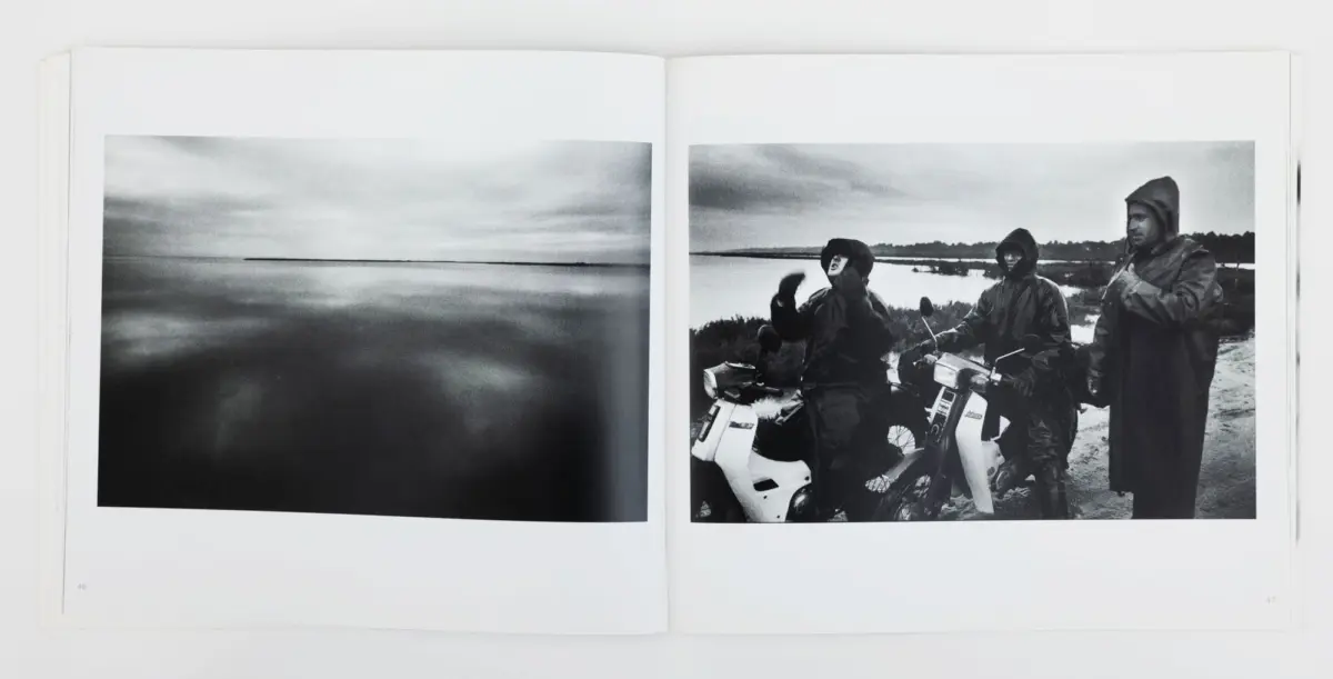 Open book two-page spread: left is tranquil seascape with distant horizon; right shows three hooded riders with motorcycles on a shore.