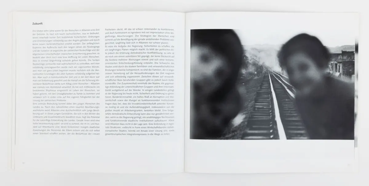 Open magazine spread: left page German text; right page shows two blurred silhouettes on a railway track with distant mountains.