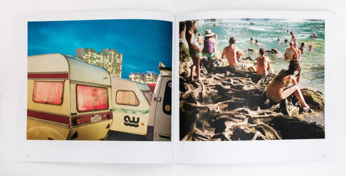 Two-page spread: left beige caravans near a lit city skyline at dusk; right people sunbathing and swimming on a rocky beach.