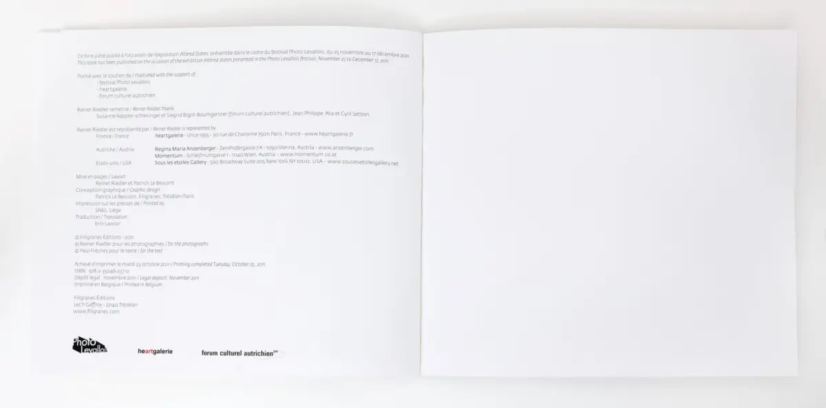 Open book on white surface; left page filled with small text, right page blank.