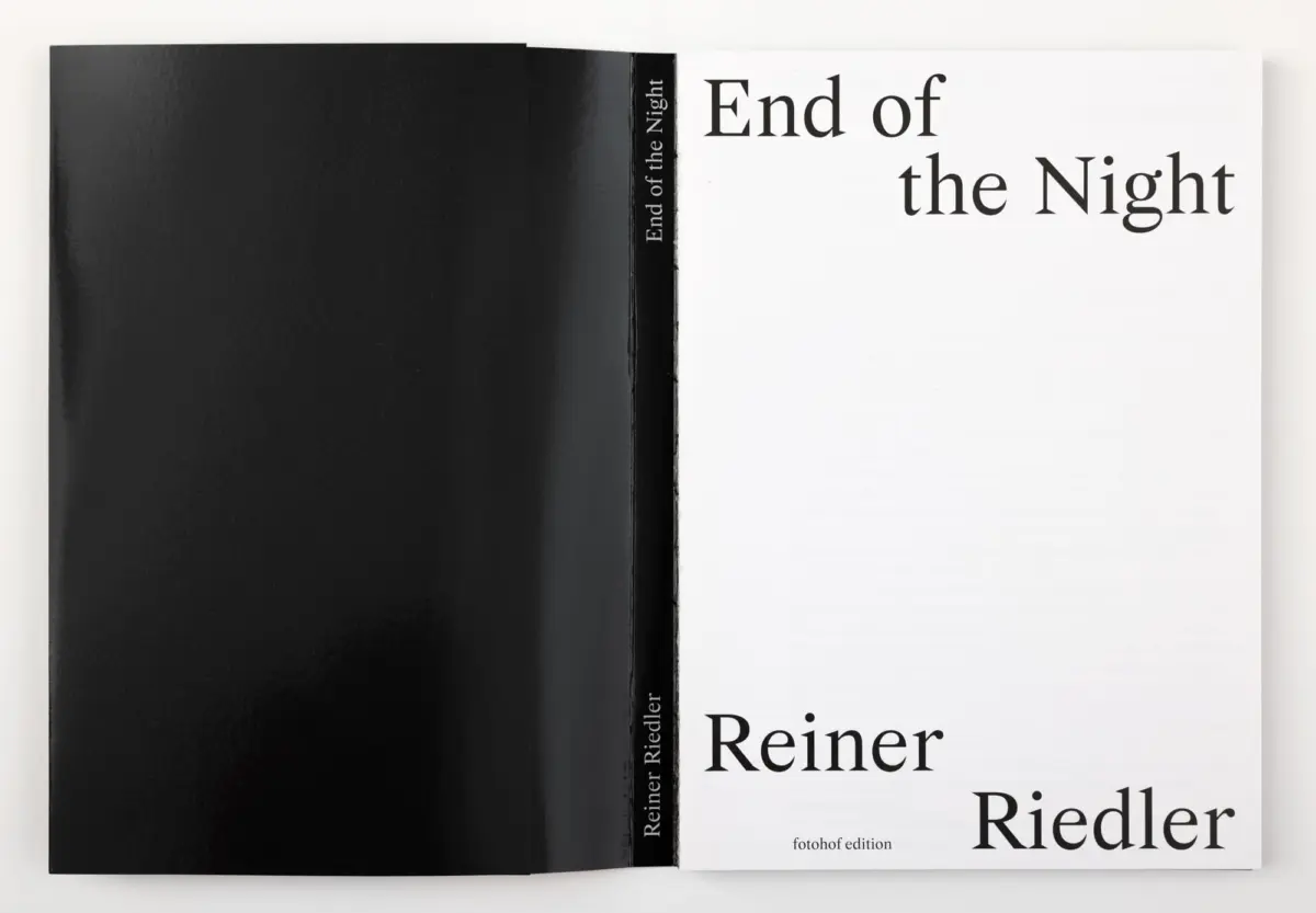 Open book spread with black left page and white right page showing bold title "End of the Night" and author "Riedler".