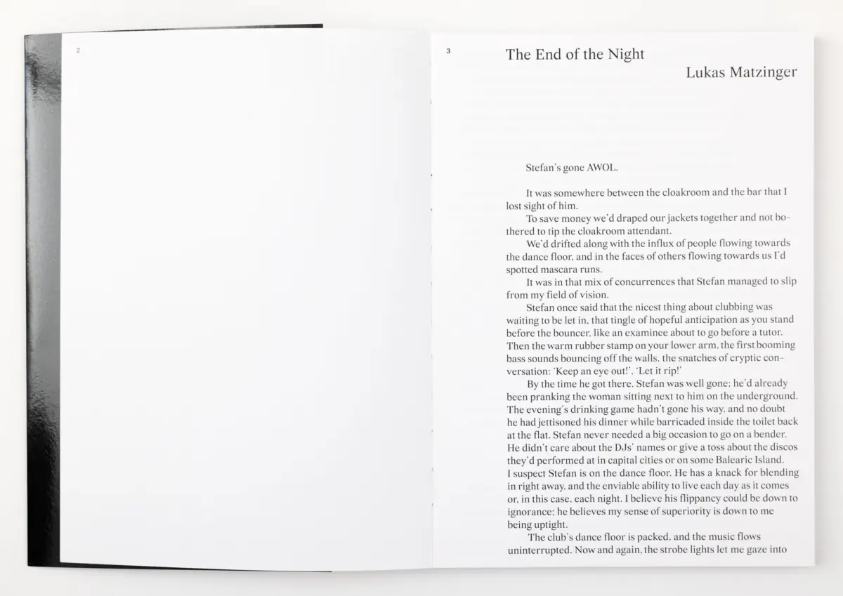 Open book on white surface; left page blank, right page shows the title The End of the Night by Lukas Matzinger with dense text.
