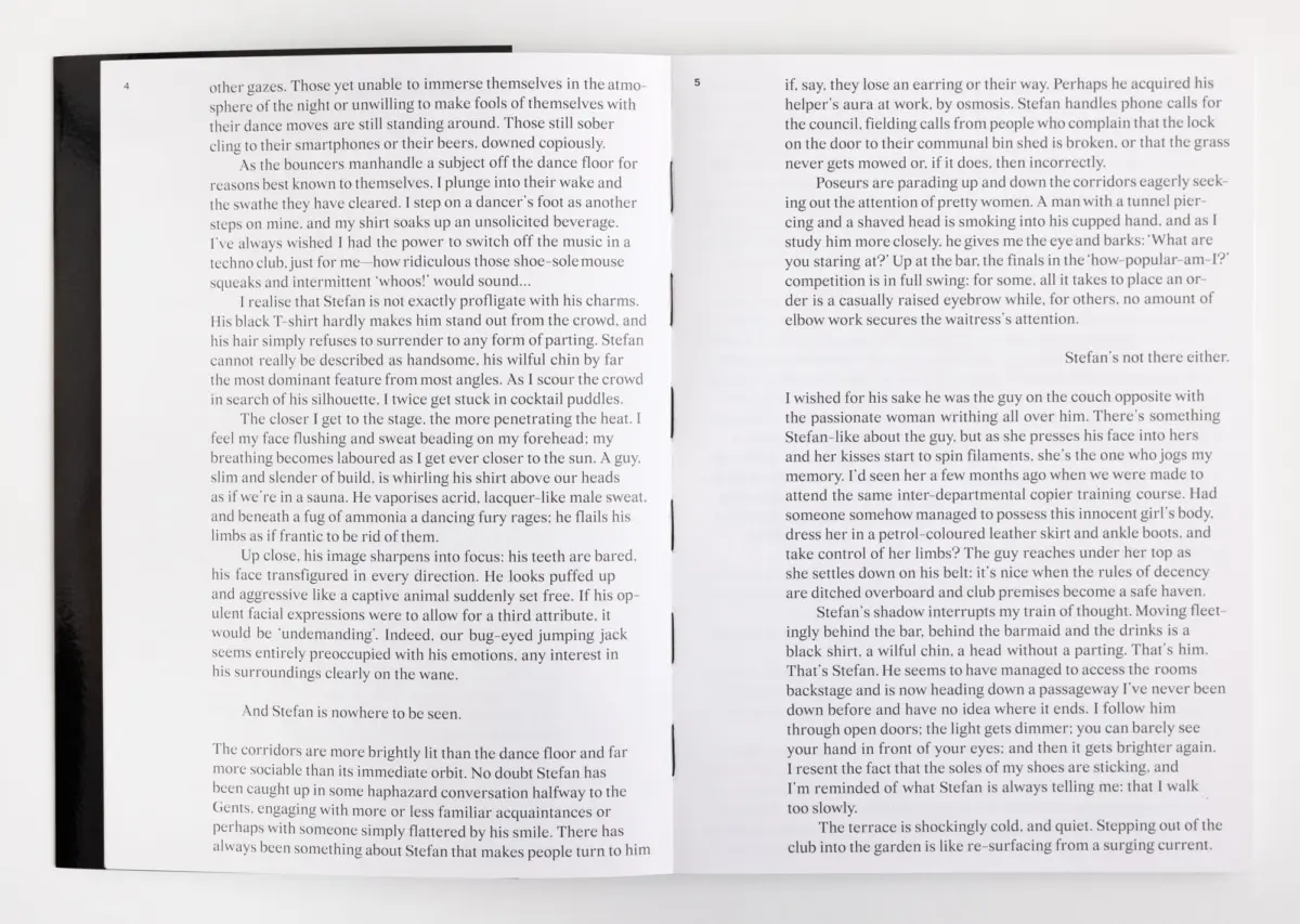 Open book on a white surface, two-page spread with dense prose and a dark spine visible.