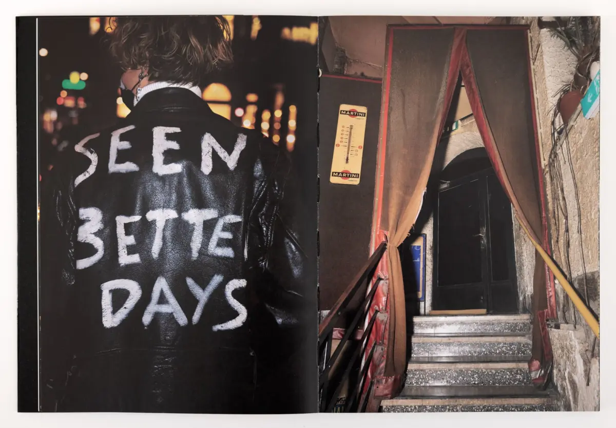 Back view of a person in a black leather jacket bearing 'SEEN BETTER DAYS' on the back, in a nighttime urban street.