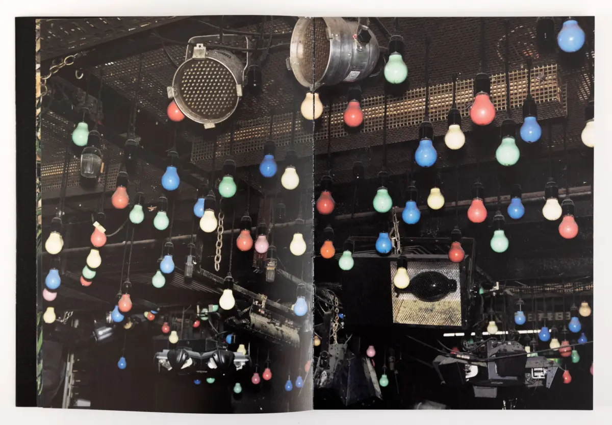 Stage ceiling with multicolored hanging light bulbs and metal rigging.