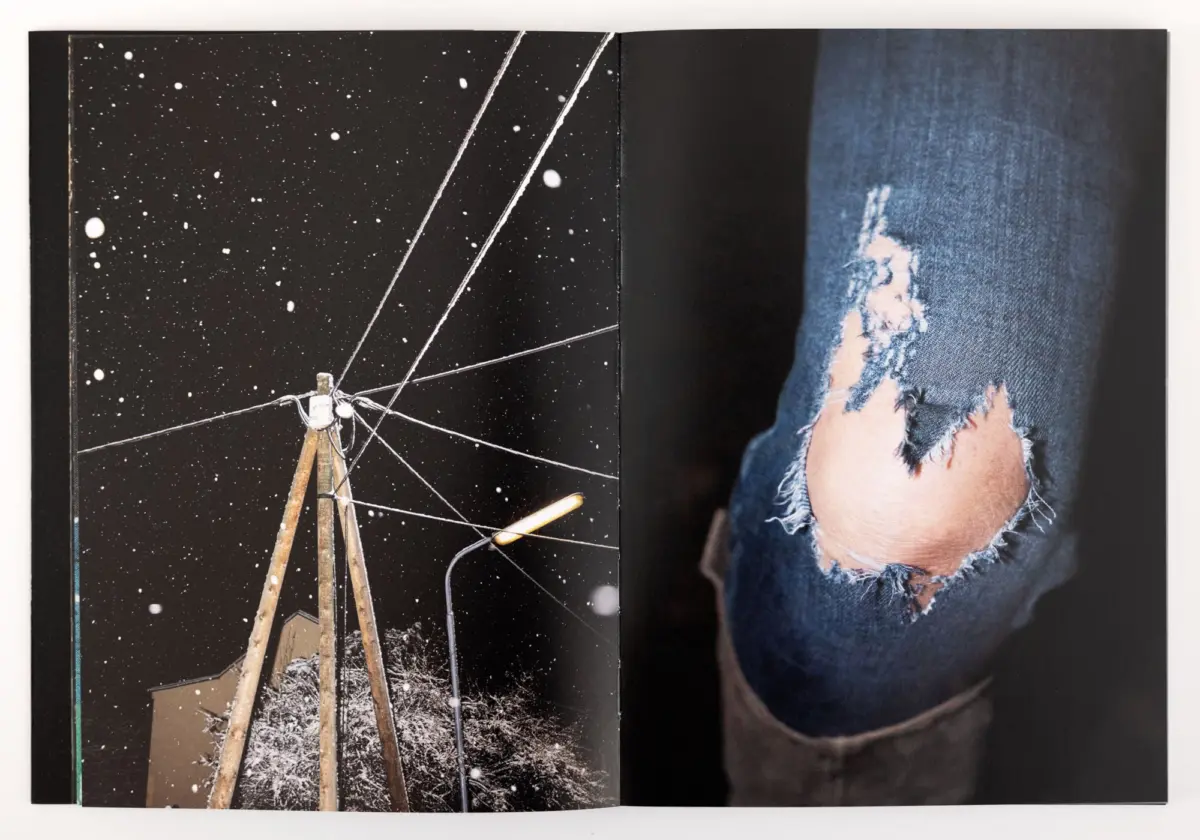 Open book spread: left page shows a wooden tripod telescope on snow under a starry sky; right page shows torn denim jeans at the knee.