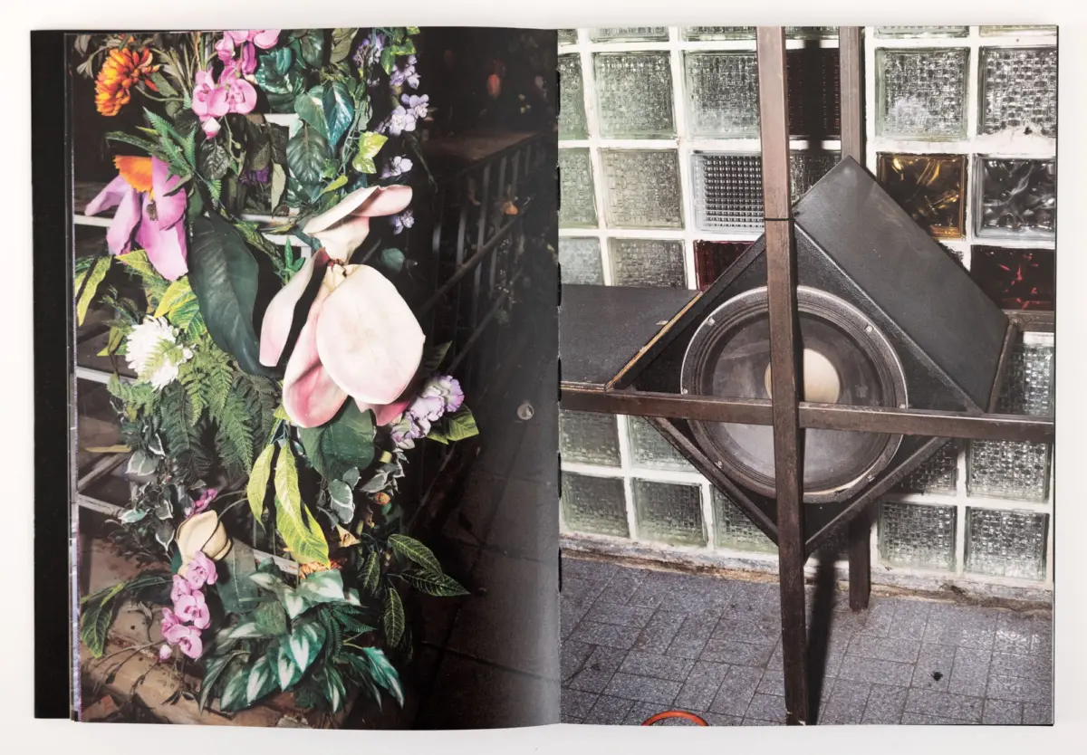 Vibrant flower bouquet with greenery on the left; a large speaker and wooden frame against a glass-block wall on the right.