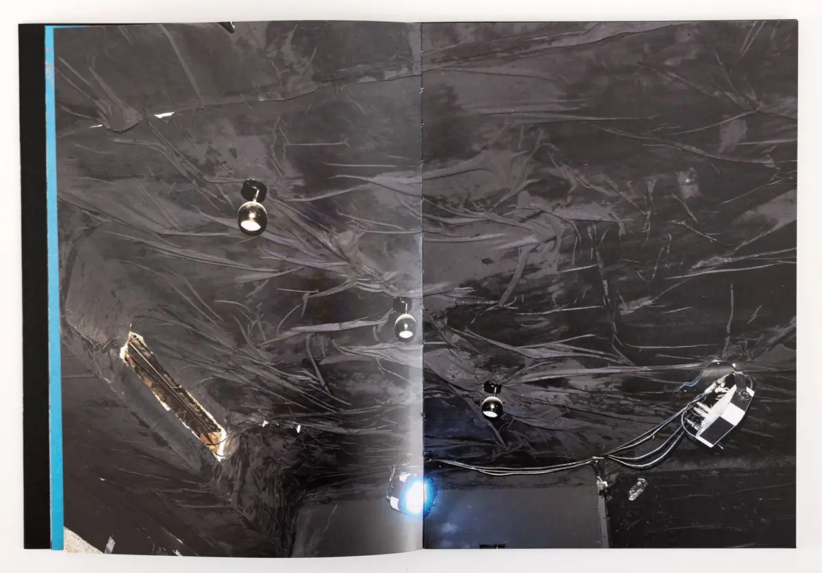 Two-page spread showing a black plastic-covered ceiling with hanging globe pendant lights; blue binding on the left.