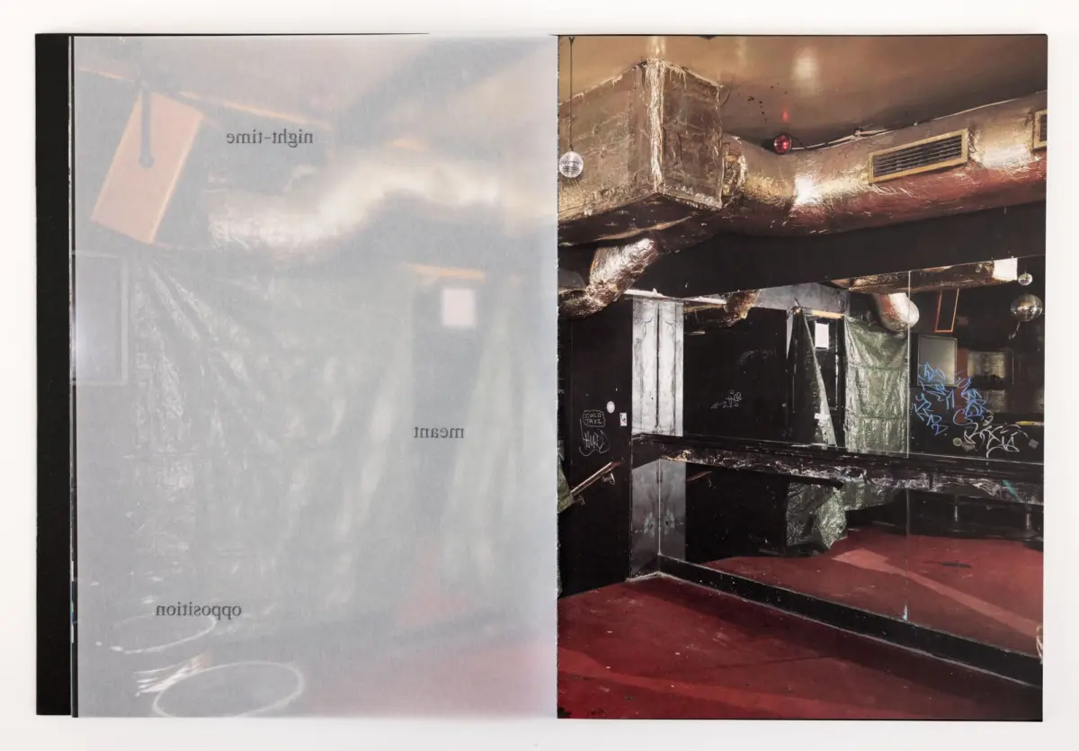 Open magazine spread; left page pale gray with reversed text, right page shows an industrial space with exposed ducts, graffiti, and disco balls.