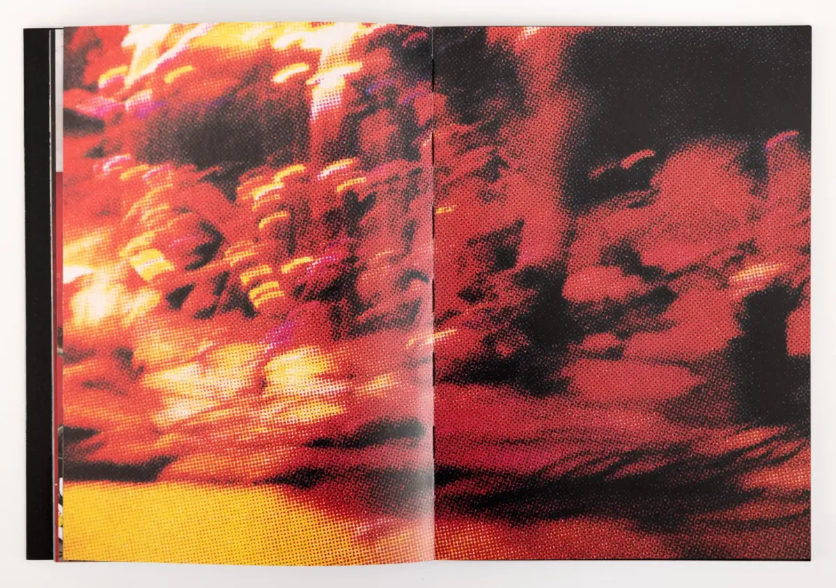 Open book displaying a fiery red-orange abstract halftone illustration across a two-page spread on a white surface.