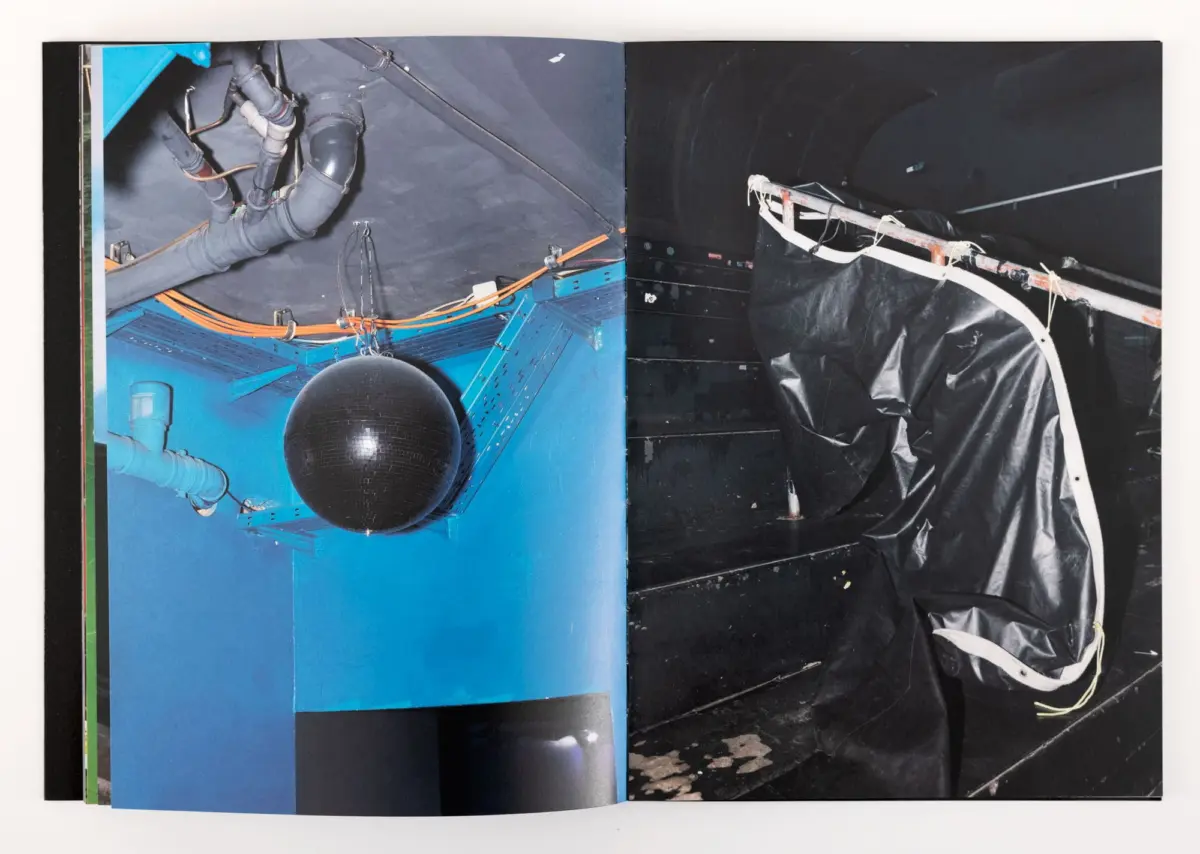 Open book spread showing blue industrial interior with exposed pipes and a black disco ball; right page shows black tarp and white frame.