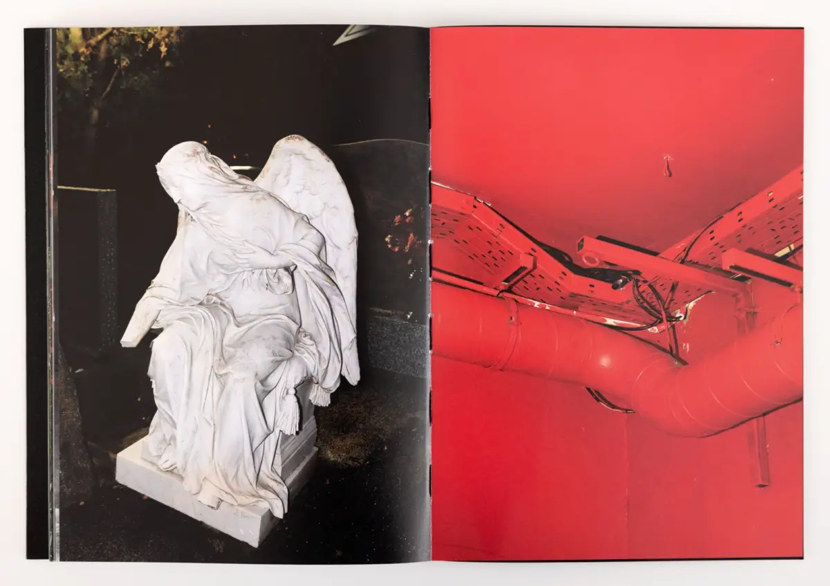 Marble statue draped in flowing robes on a pedestal in a dark outdoor setting; red pipes visible on the adjacent page.