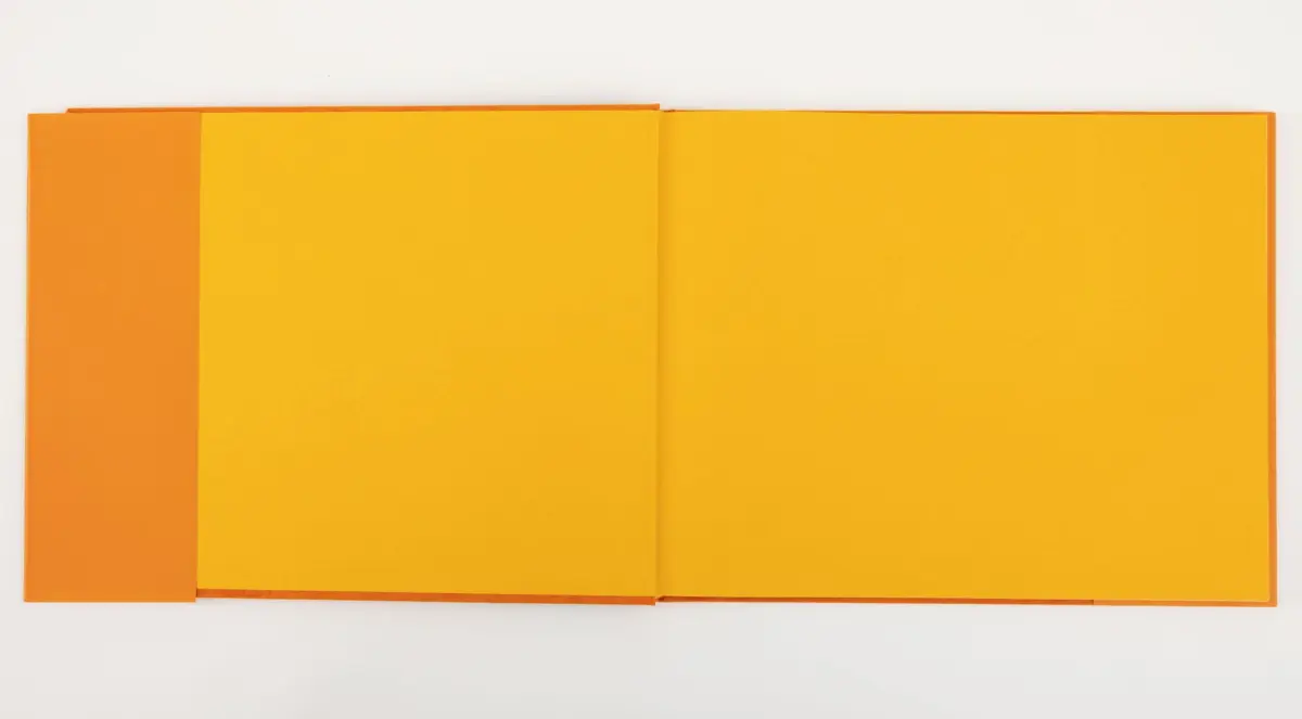 Open book with orange cover and yellow pages spread on a white surface.
