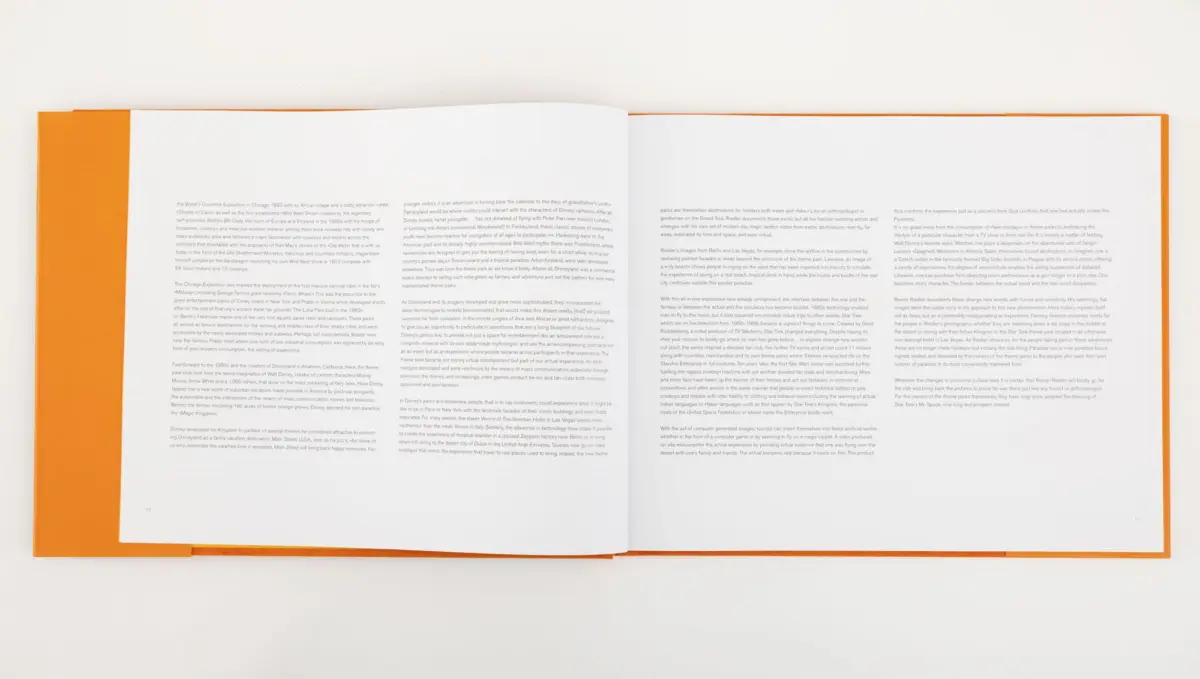 Open orange-covered book laid flat on a white surface, pages spread with small text.