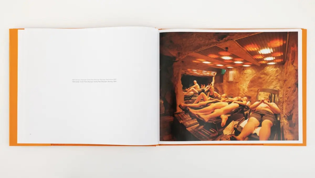 Spa guests lounging on recliners inside a rocky cave-like sauna under orange lighting.