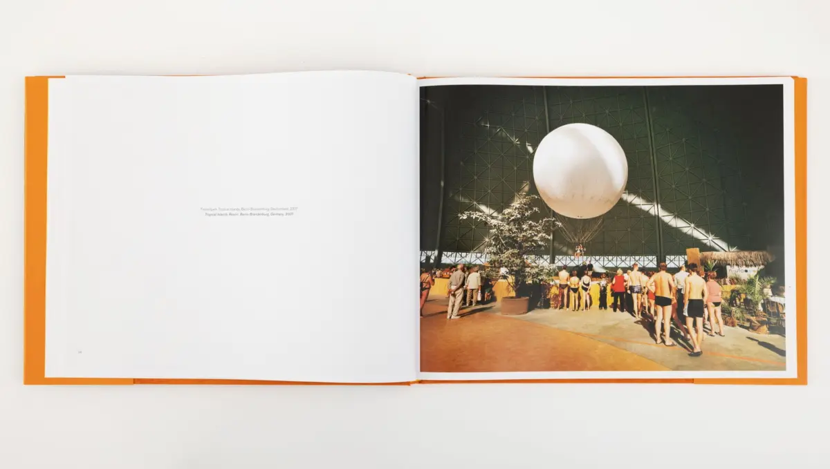 Open book; right page shows a large white spherical balloon inside a geodesic-dome indoor arena, with a crowd in swimsuits.