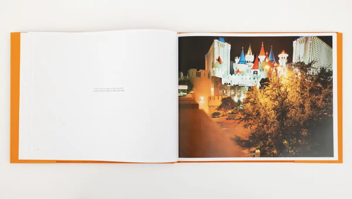 Open photo book showing Las Vegas' Excalibur Hotel at night, castle-like towers lit, trees in foreground.