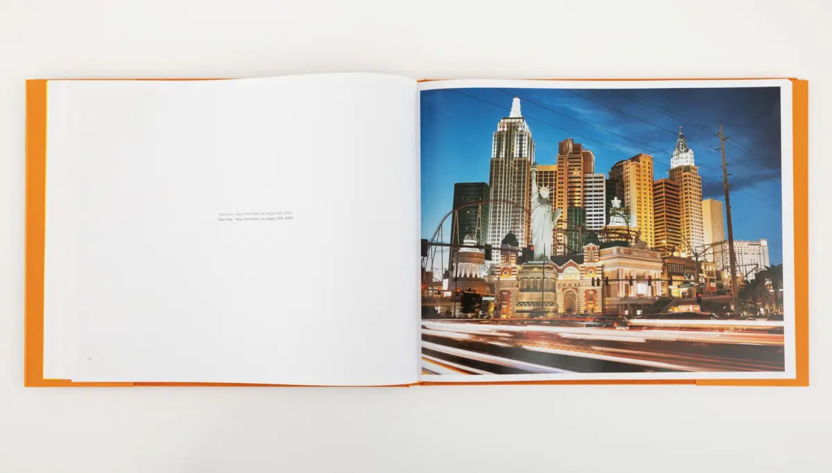 Open photo book showing Las Vegas skyline with Statue of Liberty replica and roller coaster near New York-New York Hotel.