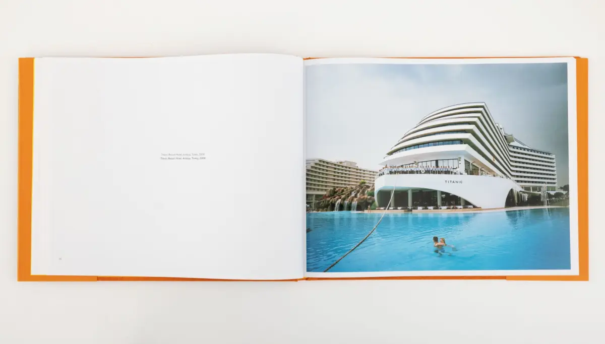 Open photo book displaying the Titanic cruise ship at a seaside resort with a large pool.