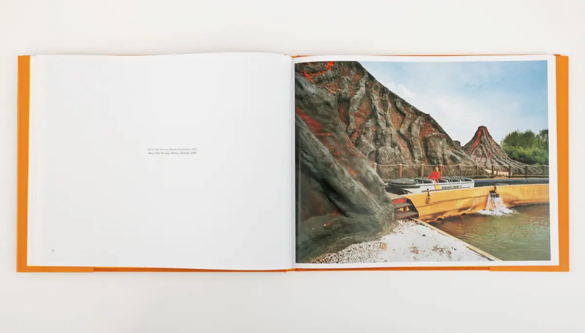 Person in a red shirt sits in a yellow boat on a river beside jagged lava-rock formations.