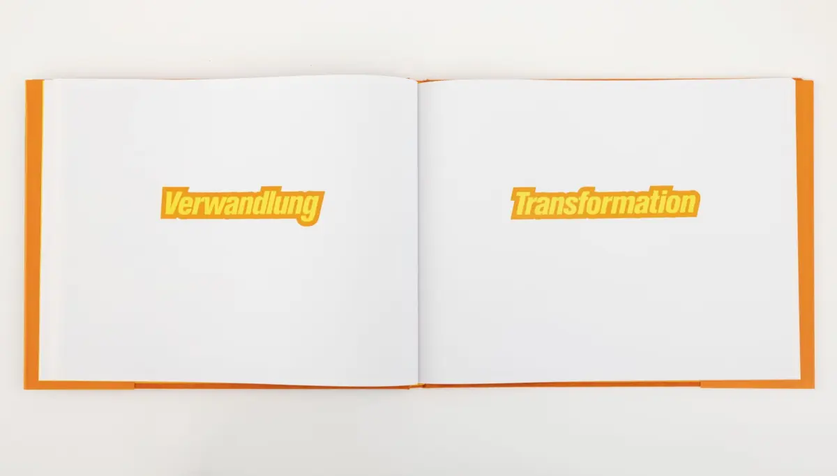 Open book on white background with orange spine; left page shows Verwandlung, right page shows Transformation in orange text.