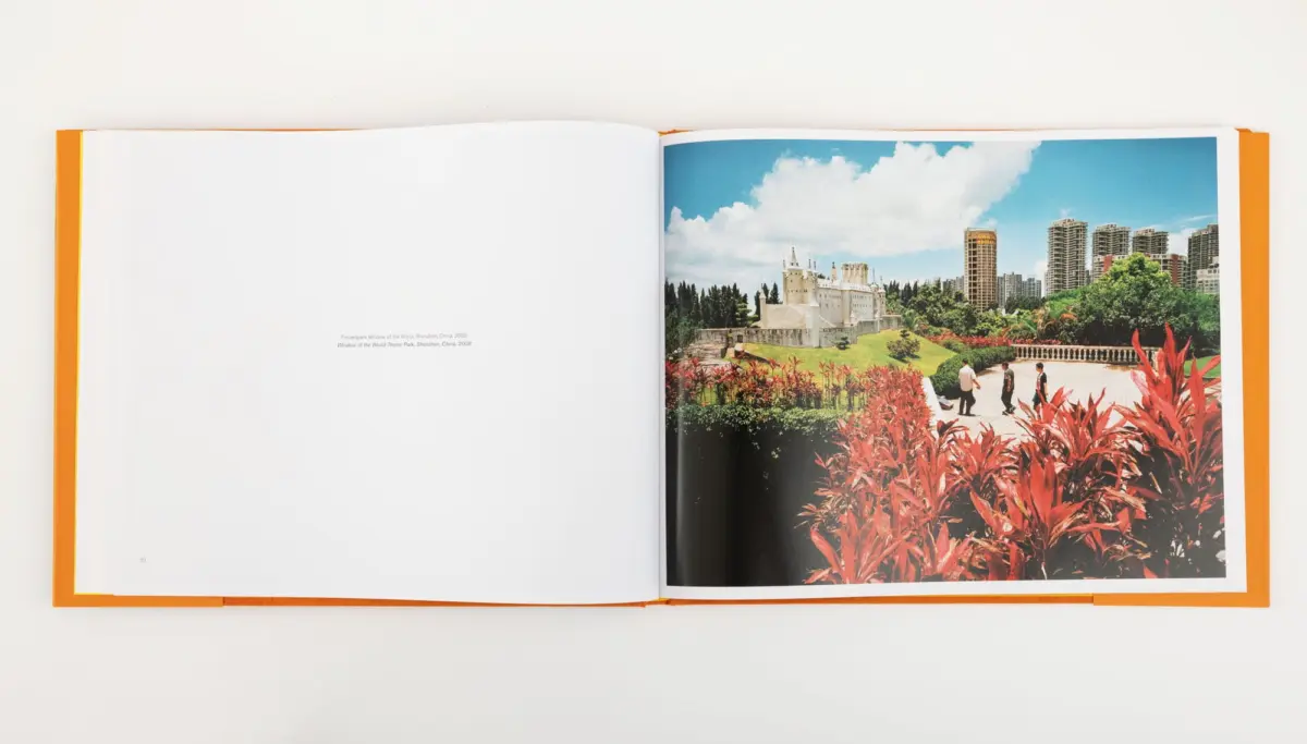 Open book; right page shows a city park with red foliage, people walking, a fortress-like white building, and modern high-rises under a blue sky.