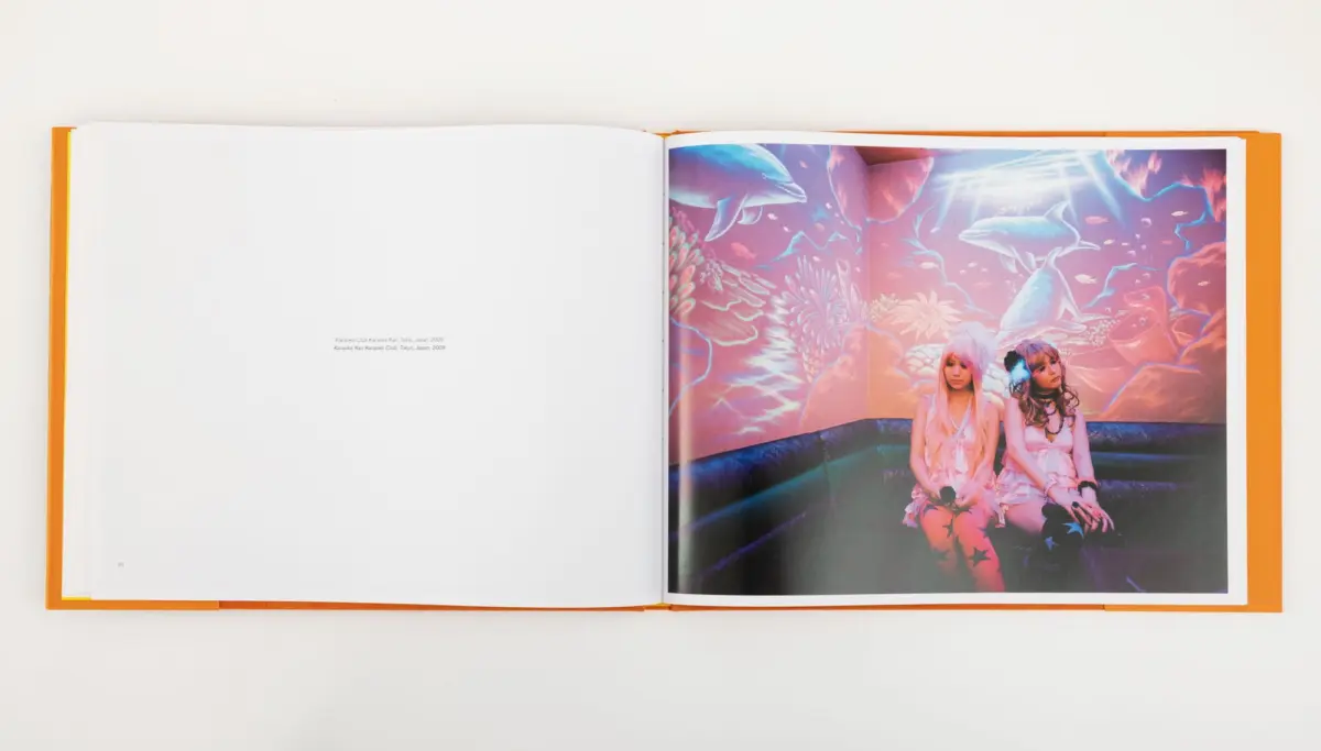 Two people in pink outfits sit in a neon underwater scene with dolphins and coral.