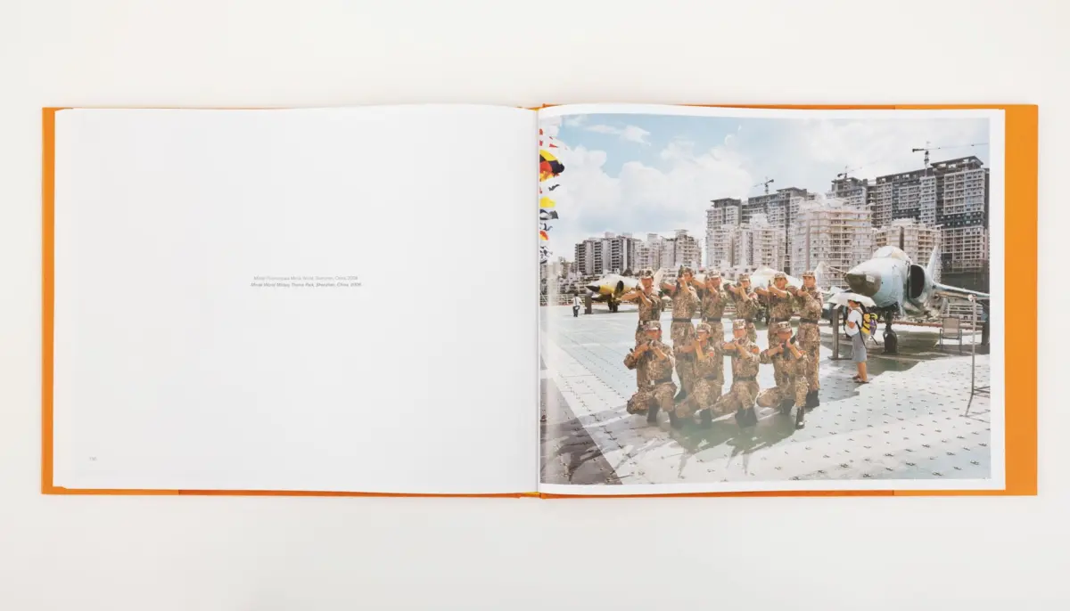 Open book displaying a photo of military personnel posing on a flight deck beside a fighter jet with a city skyline in the background.