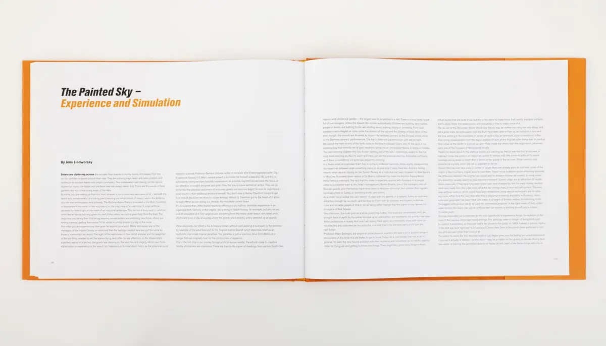 Open book spread on white surface with orange cover; left page features the title The Painted Sky – Experience and Simulation.