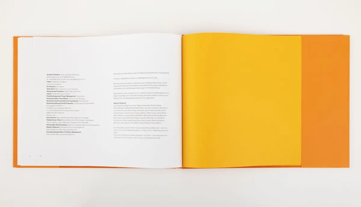 Open hardcover book with orange cover and yellow inner pages, laid flat on a white surface.