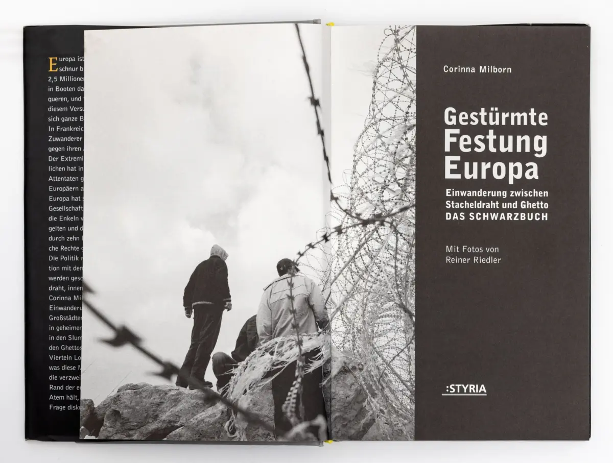 Open book spread; black-and-white photo of people climbing rocks beside barbed wire, with bold German title Gestürmte Festung Europa on the right.