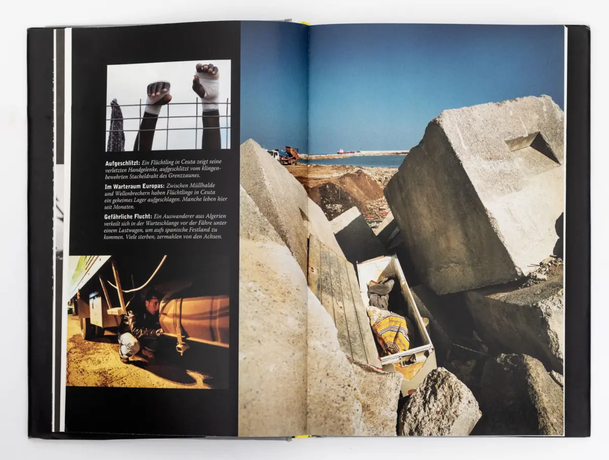 Arms with bandaged wrists raised through a wire fence; opposite page shows a rubble-strewn coastal construction site with large concrete blocks.