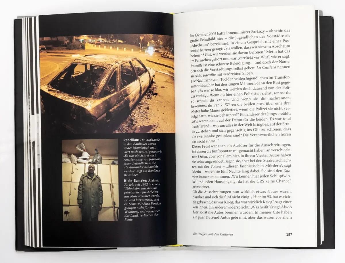 Open book showing nighttime city street photo of a charred sedan wreck