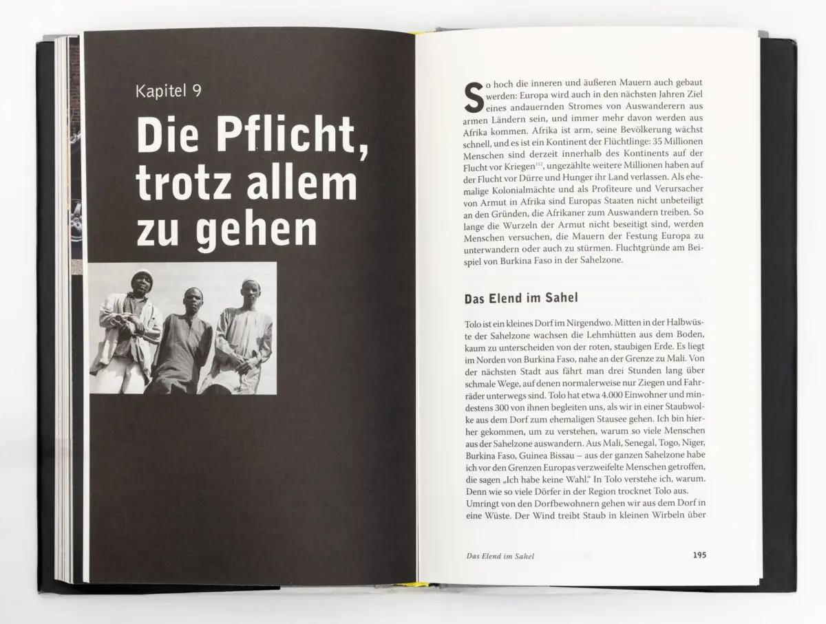 Open book showing Chapter 9 title on dark left page; right page densely printed German text; small black-and-white photo of three men at bottom left.