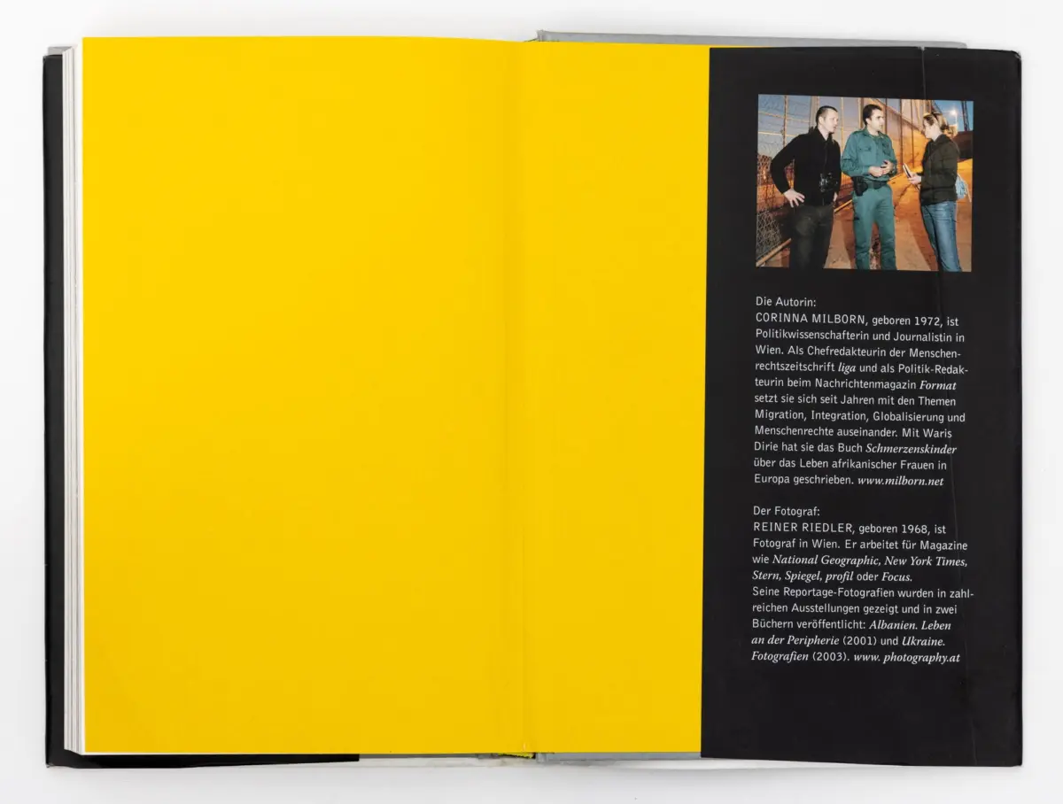 Three adults converse on a bridge beside a chain-link fence at dusk; photo inset on a black page of a bright yellow book spread.