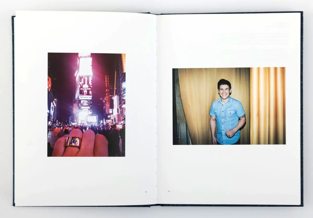 Open book with two photos: left, neon-lit city street at night; foreground hand with ring; right, person in blue shirt smiling before beige curtains.