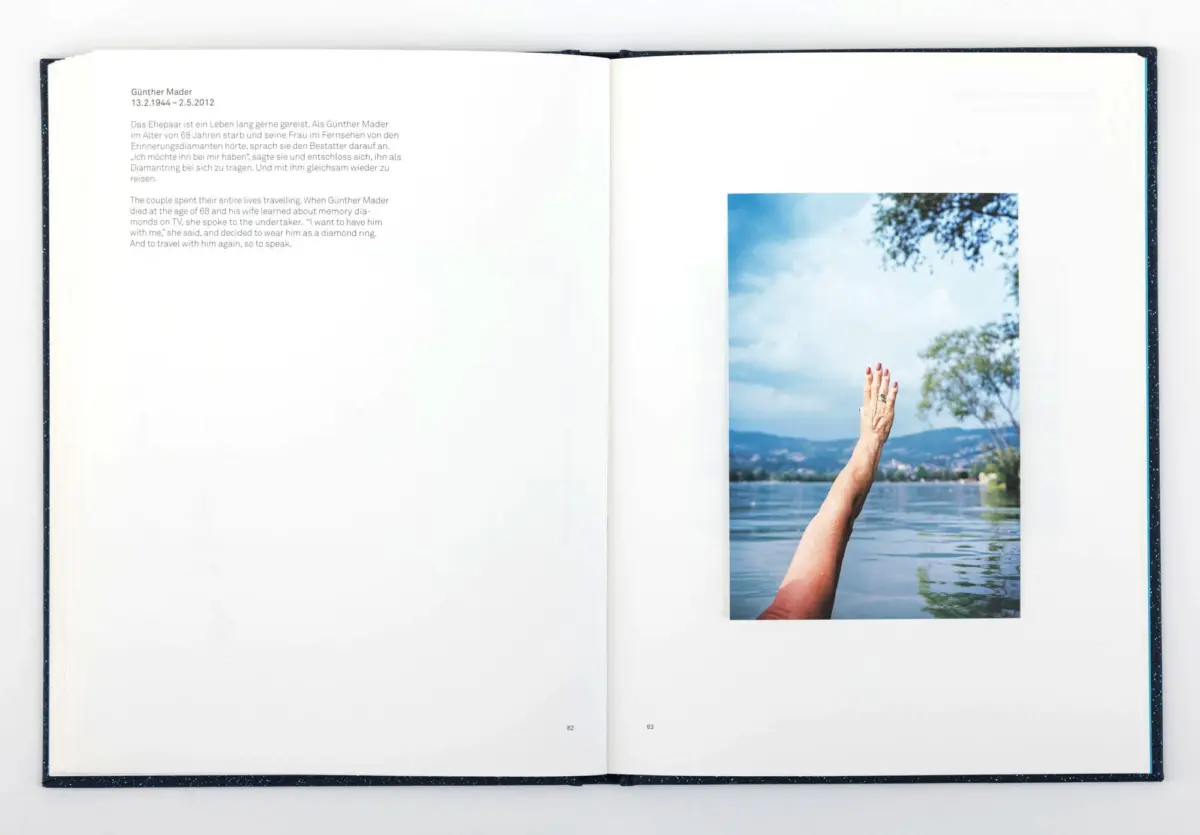 Open book; right page shows a raised hand with rings and red nails over a lake, with distant mountains and a blue sky.