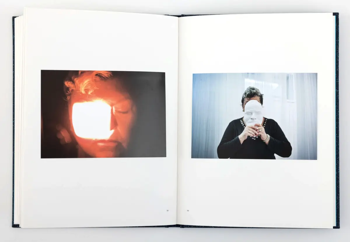 Open photo book with two portraits: left, bright light over a person's face; right, person in black with white mask held over face.