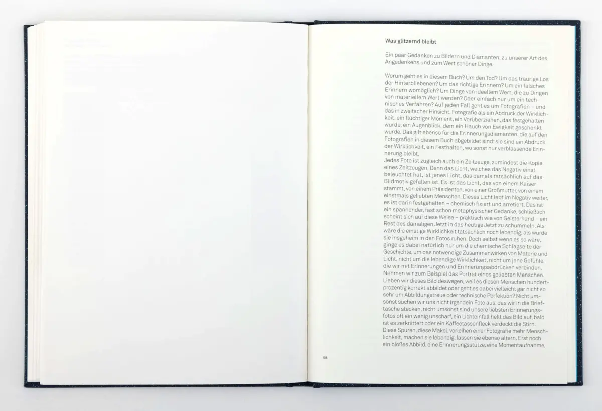 Open hardcover book on white surface; right page densely printed German text, left page mostly blank.