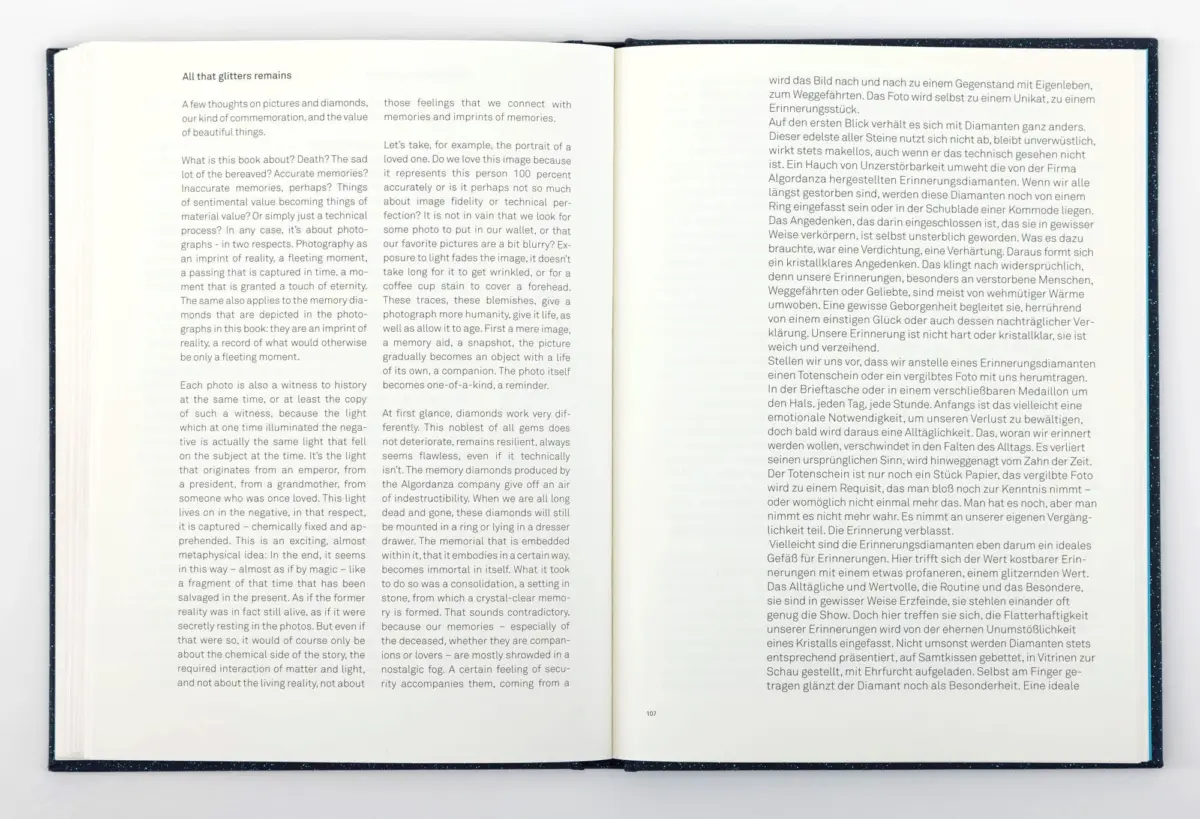 Open blue-speckled hardcover book on a flat surface, two-page spread of dense English and German text.