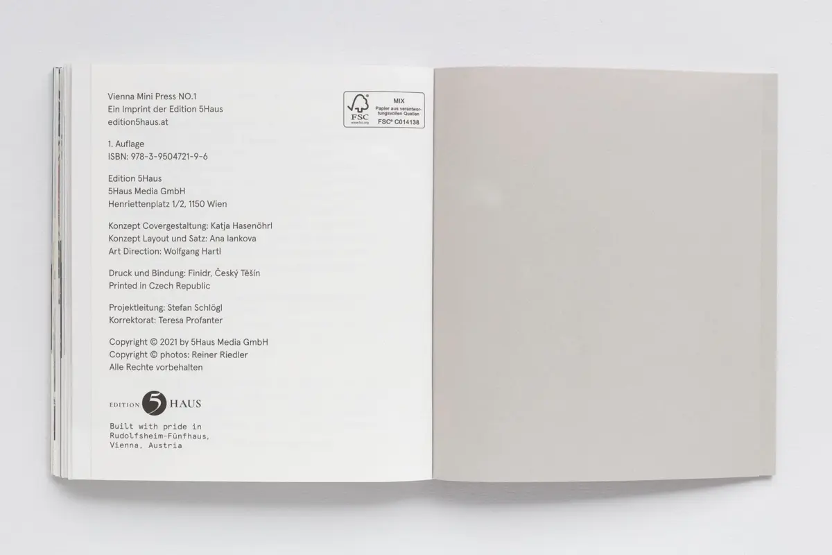 Open book on a white surface; left page displays publication details and FSC logo, right page is plain gray.