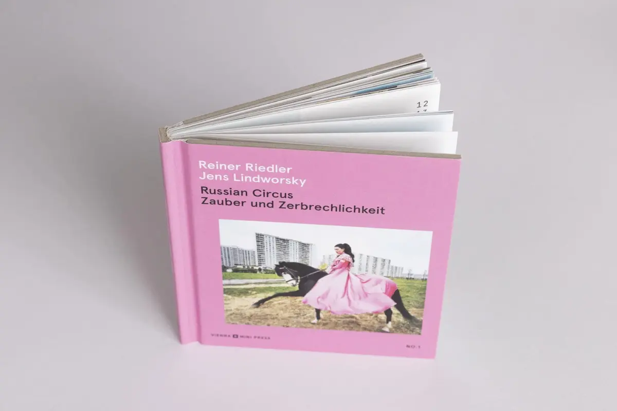 Pink book cover featuring a rider in a pink dress on a black horse in a grassy field with buildings in the background.