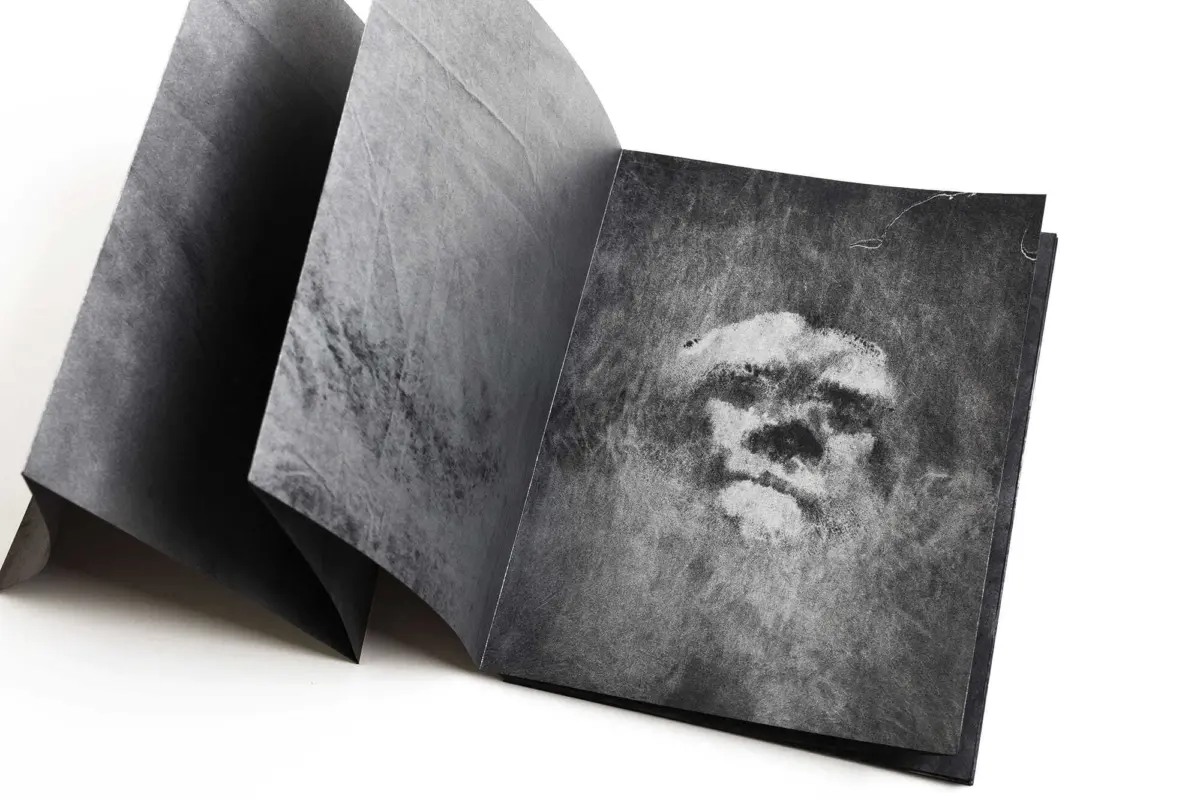 Diagonally arranged folded gray-black paper sheets against a white studio background.