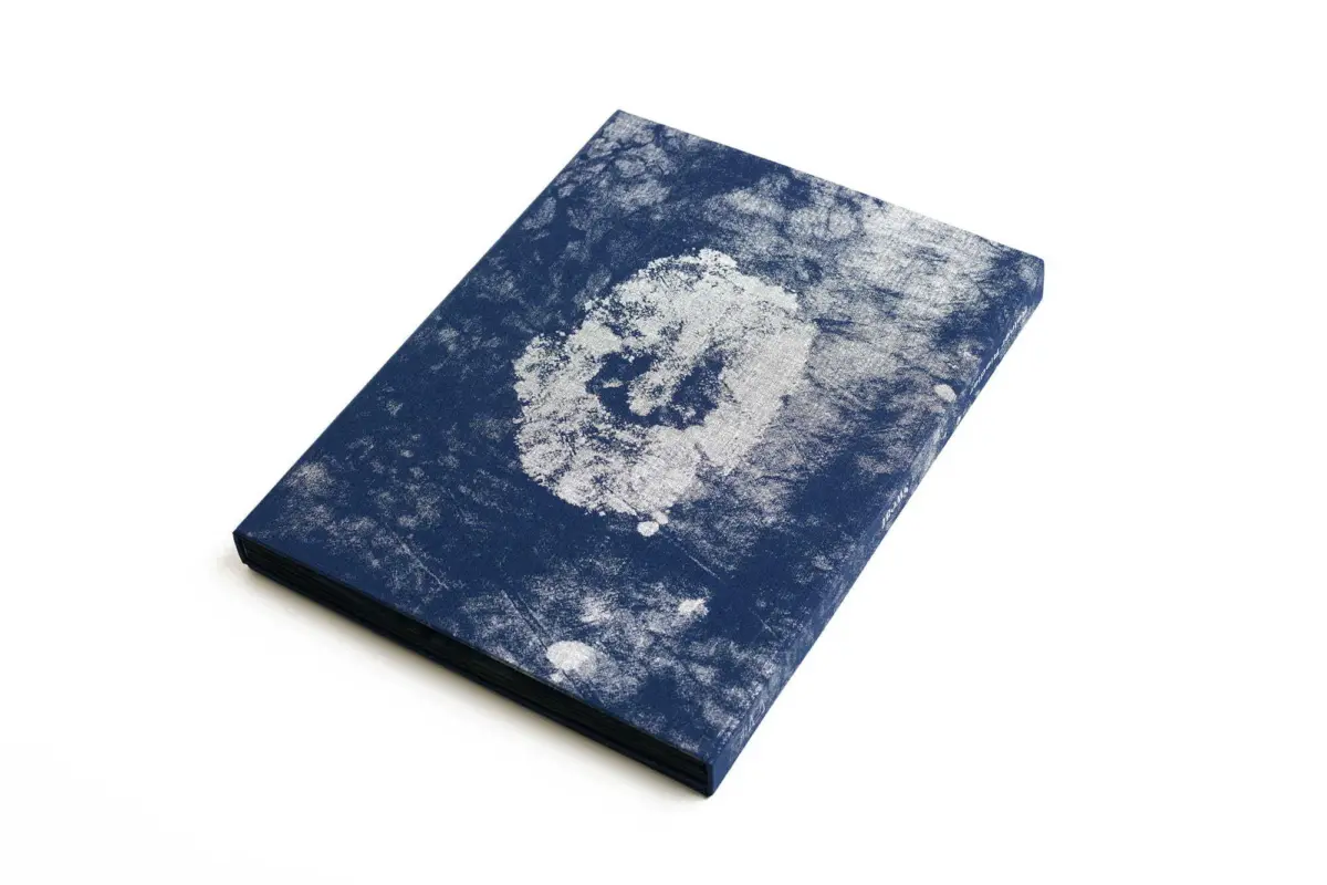 Blue notebook resting on a white background with a white powdery circular stain on its cover.