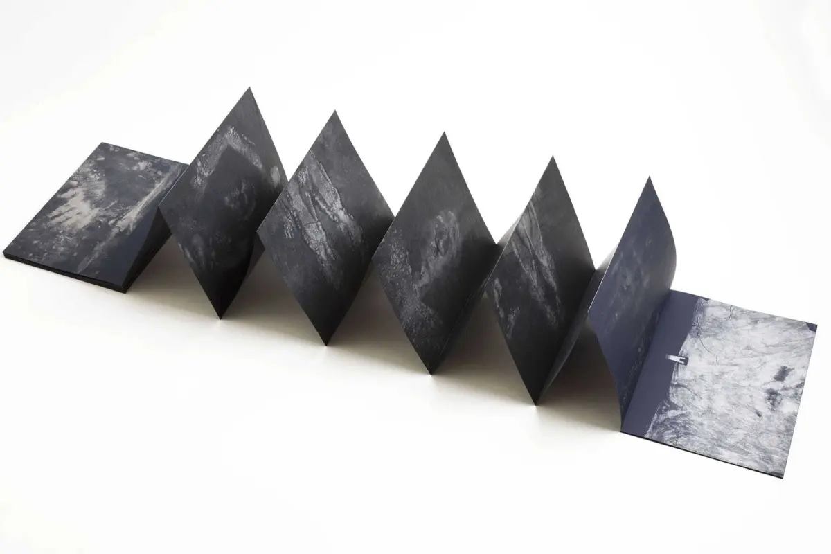 Accordion-folded black marble-pattern panels form a zigzag line on a white studio background.