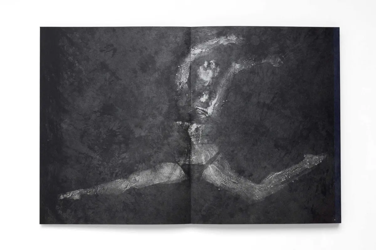 Open hardcover book with dark marbled pages and blue spine, laid flat on a white surface.