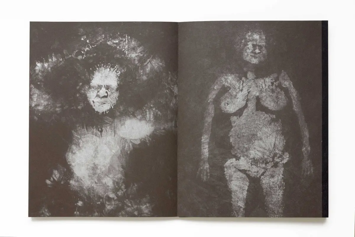 Open book on a white surface displaying two grainy, sepia-toned portraits on brown pages.