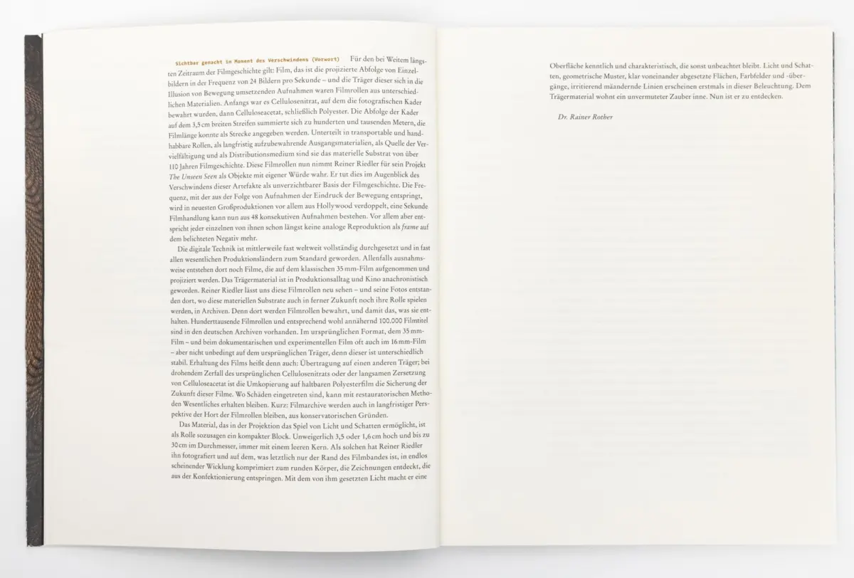 Open hardcover book showing a two-page spread of dense German text, brown patterned spine, on a white surface.