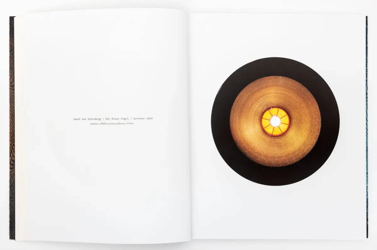 Open book, right page shows a large vinyl record with an orange center label and black outer edge; left page blank.